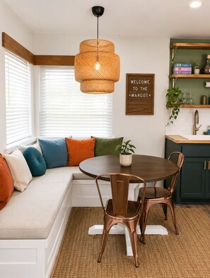 A modern kitchen with a built-in bench seating area, a round dining table, and a hanging light fixture. - OKC 1 Bed 1 Bath Mini Guesthouse - The Margot (Oklahoma City)
