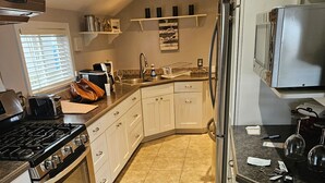 A kitchen with white cabinets, a stove, oven, and a refrigerator.