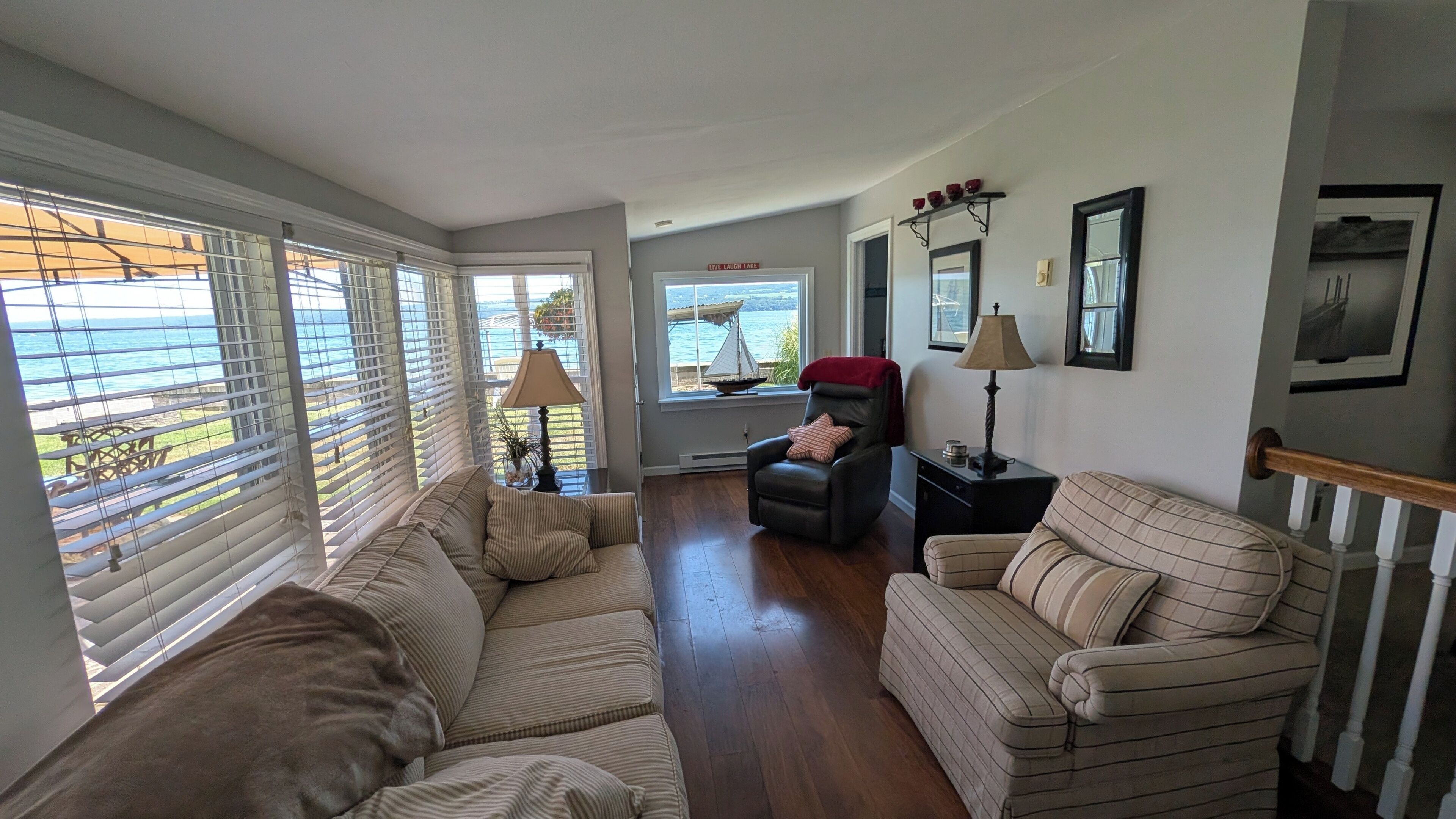 A living room with a view of the lake, a sofa, a recliner, and a lamp.