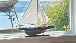 A model sailboat on a windowsill with a view of a lake and a sign above reading 'LIVE LAUGH LAKE'.