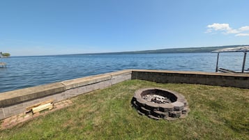Une terrasse au bord du lac, avec un foyer et un mur de pierre donnant sur l’eau.