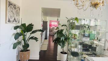 A hallway with a chandelier, potted plants, a glass display case, and a world map on the wall.