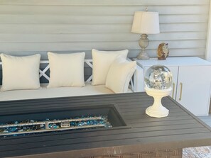 A white sofa with cushions, a small table with a decorative item, and a cabinet with gold handles.