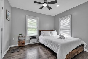 Ein Schlafzimmer mit einem Bett, Nachttischen, einem Heizgerät und einem Deckenventilator.
