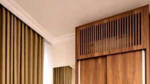 A room with a wooden wardrobe, a round stool, and a mirror. - Tramontan Serviced Apartments (HAIL)