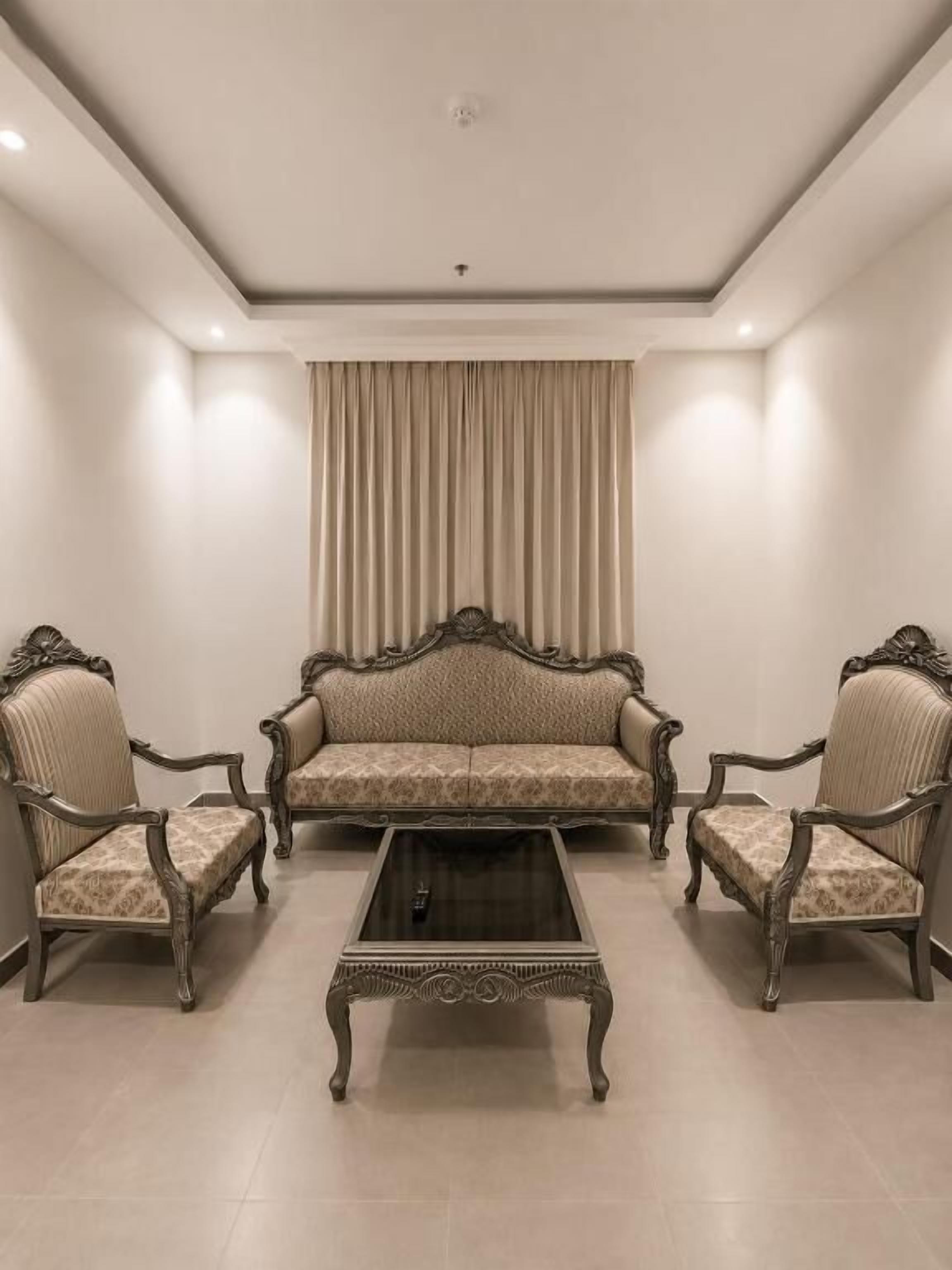 A room with a sofa set, two armchairs, and a coffee table.