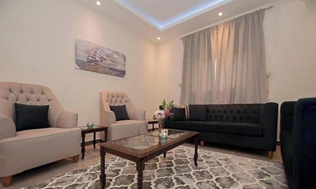 Ein Wohnzimmer mit einem beigen Sofa, einem dunklen Sofa und einem Glastisch.
