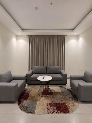 Una sala de estar moderna con un sofá gris, una mesita redonda y un tapete estampado.