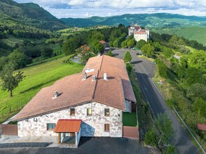 A stone building with a red-tiled roof, a small attached structure, and a paved road. - La Aparecida Tourist Lodging, set in a natural setting with fabulous views. (Ampuero)