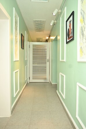 A hallway with a door, framed artwork on the walls, and a ceiling with recessed lighting. - Luxury 3BR Apartment off Toyin Str | 3 Queen Beds (Lagos)