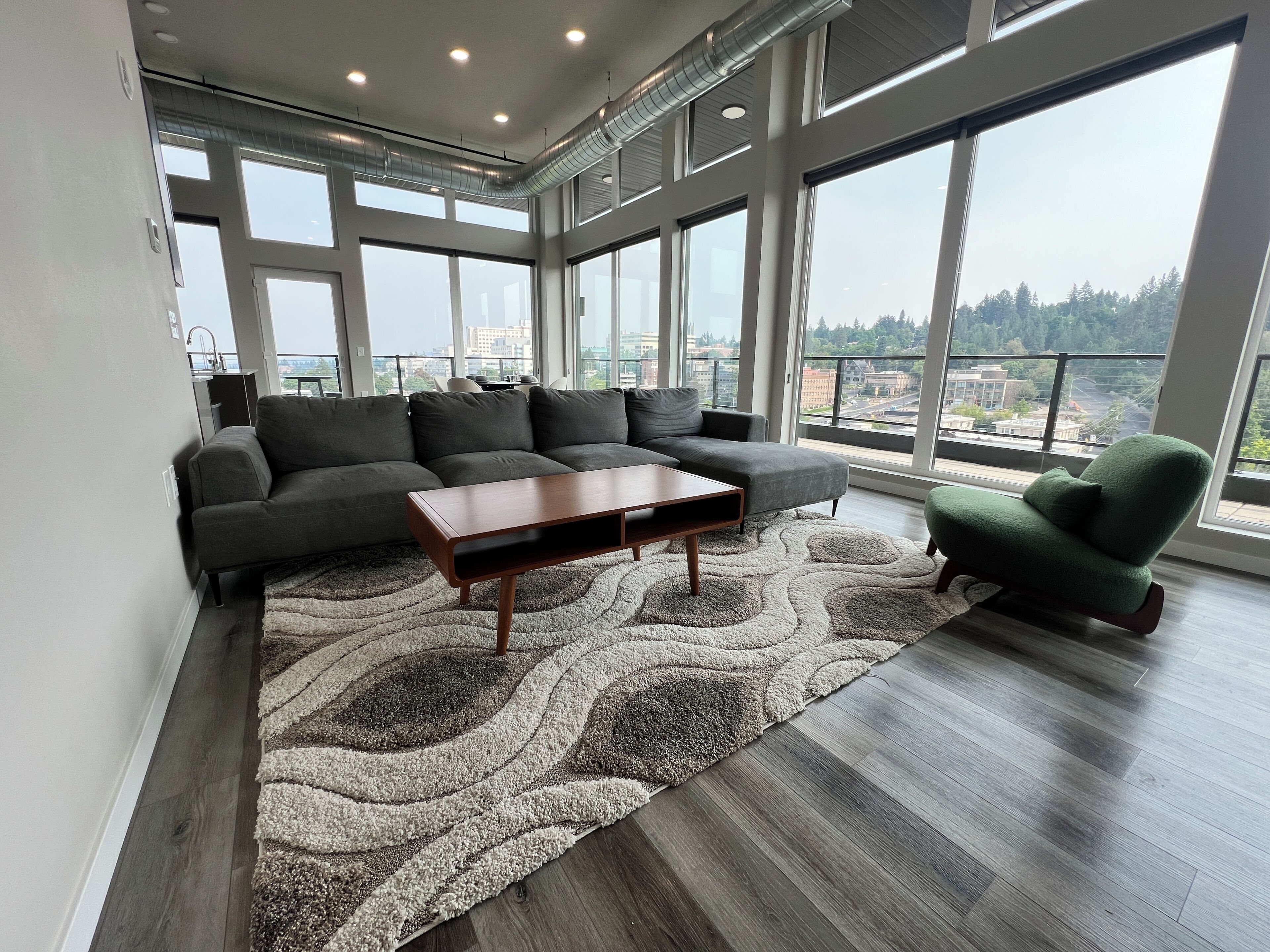 A modern living room with a sectional sofa, a coffee table, and a green armchair.