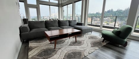 A modern living room with a sectional sofa, a coffee table, and a green armchair.