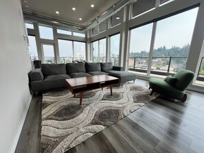 Ein modernes Wohnzimmer mit einem Ecksofa, einem Couchtisch und einem grünen Sessel.