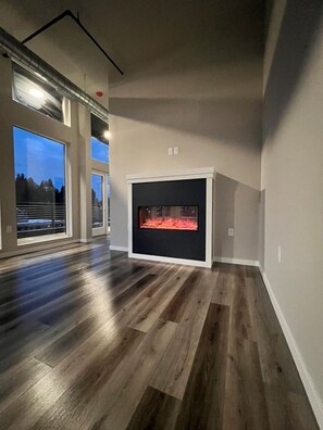 Ein geräumiges Zimmer mit Kamin, großen Fenstern und Holzboden.