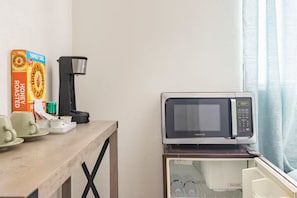 A kitchenette with a microwave, a coffee maker, and a box of honey bunches of oats.