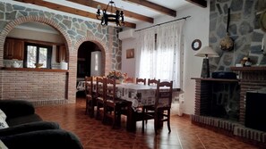 A dining area with a stone archway, wooden dining table, chairs, and a fireplace. - Casa Miranda Cómpeta by Ruralidays (Málaga)