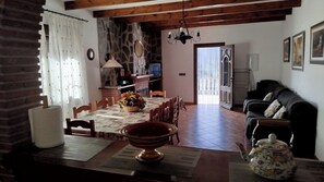 A dining area with a table, chairs, a chandelier, and a kitchen in the background. - Casa Miranda Cómpeta by Ruralidays (Málaga)