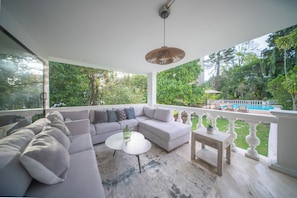 A modern living room with a sectional sofa, a coffee table, and a small table with a lamp. - The Garden Mansion | 11 bedrooms with a club lounge•Jacuzzi•Olympic Pool•Cleaning Lady•Air Conditioning (Medellín)