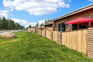 A row of log cabin-style cabins with a grassy yard and a red umbrella. - Tahoe Keys Studio Retreat - HOA Amenities (South Lake Tahoe)