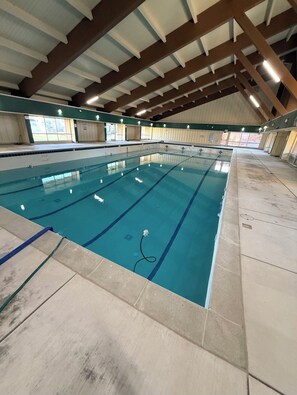 An indoor swimming pool with clear lanes, a tiled floor, and a high ceiling with wooden beams. - Tahoe Keys Studio Retreat - HOA Amenities (South Lake Tahoe)