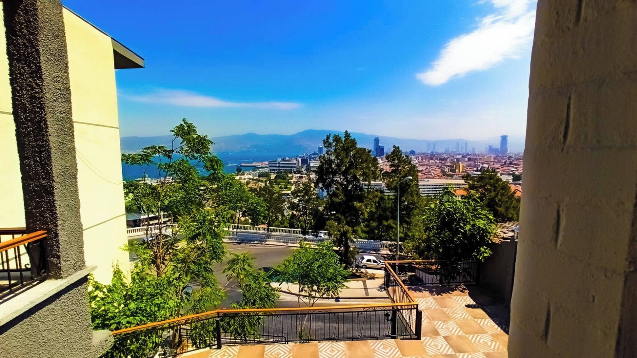 A balcony with a view of a cityscape, including buildings and a body of water.