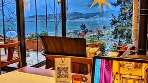 A room with a view of a body of water and mountains, a star decoration, a laptop, and a QR menu sign.