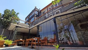 A modern building with a glass facade, outdoor seating area, and a balcony.