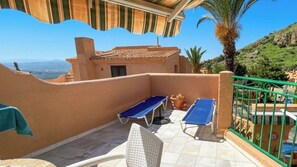 Eine Terrasse mit zwei Liegestühlen, einem Tisch und einem Stuhl.