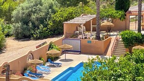 Ein Poolbereich mit Liegestühlen, ein kleines Gebäude mit Dach und eine Treppe.