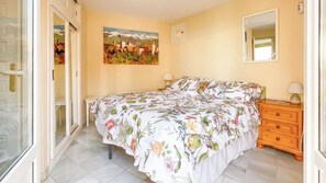 A bedroom with a bed, a nightstand, a mirror, and a painting on the wall.
