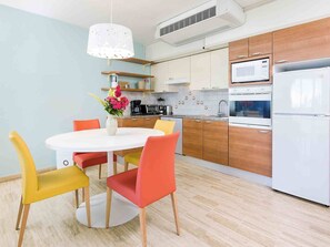 A modern kitchen with a round dining table, colorful chairs, and a white refrigerator. - Minutes from Maho Beach and Mullet Bay Beach (Maho Bay)