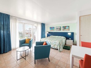 A hotel room with a bed, two armchairs, a small table, and a view of buildings outside. - Minutes from Maho Beach and Mullet Bay Beach (Maho Bay)