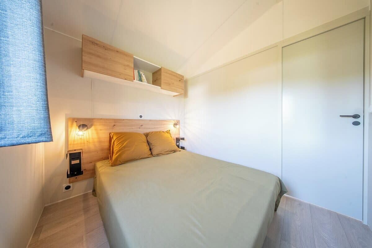 Une chambre à coucher comprenant un lit, des tables de chevet, une armoire et des étagères intégrées.