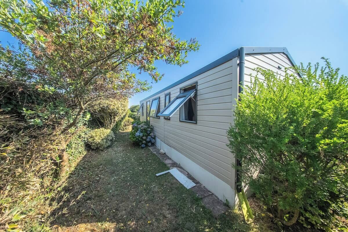 En campingvogn med en lille forhave, et vindue og en dør.