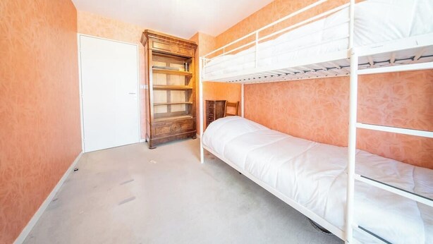 Een slaapkamer met een stapelbed, een houten garderobe, een witte deur en een lamp.