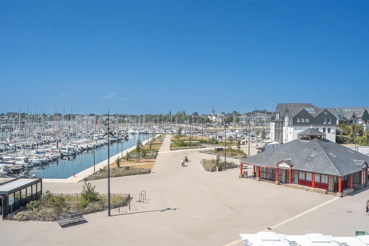A marina with numerous boats, a covered building, and a clear sky.