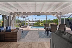 A covered outdoor area with a pool, seating, and a view of the surrounding landscape. - Pool, Sunsets and Water Access! 3-bedroom house in lovely Cape Coral (Cape Coral)