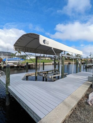 A dock with a covered seating area, a boat, and a clear sky. - Pool, Sunsets and Water Access! 3-bedroom house in lovely Cape Coral (Cape Coral)
