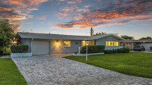 Une maison d’habitation avec une allée pavée, un garage et une pelouse bien entretenue.