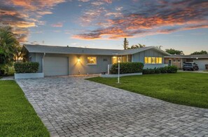 A residential house with a paved driveway, a garage, and a well-maintained lawn. - Pool, Sunsets and Water Access! 3-bedroom house in lovely Cape Coral (Cape Coral)