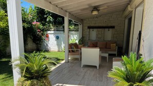 A covered patio area with a seating arrangement, potted plants, and a stone wall. - Spacious 4-bedroom home-sleeps 9 with AC in all rooms-3 minutes from the sea! (Çeşme)