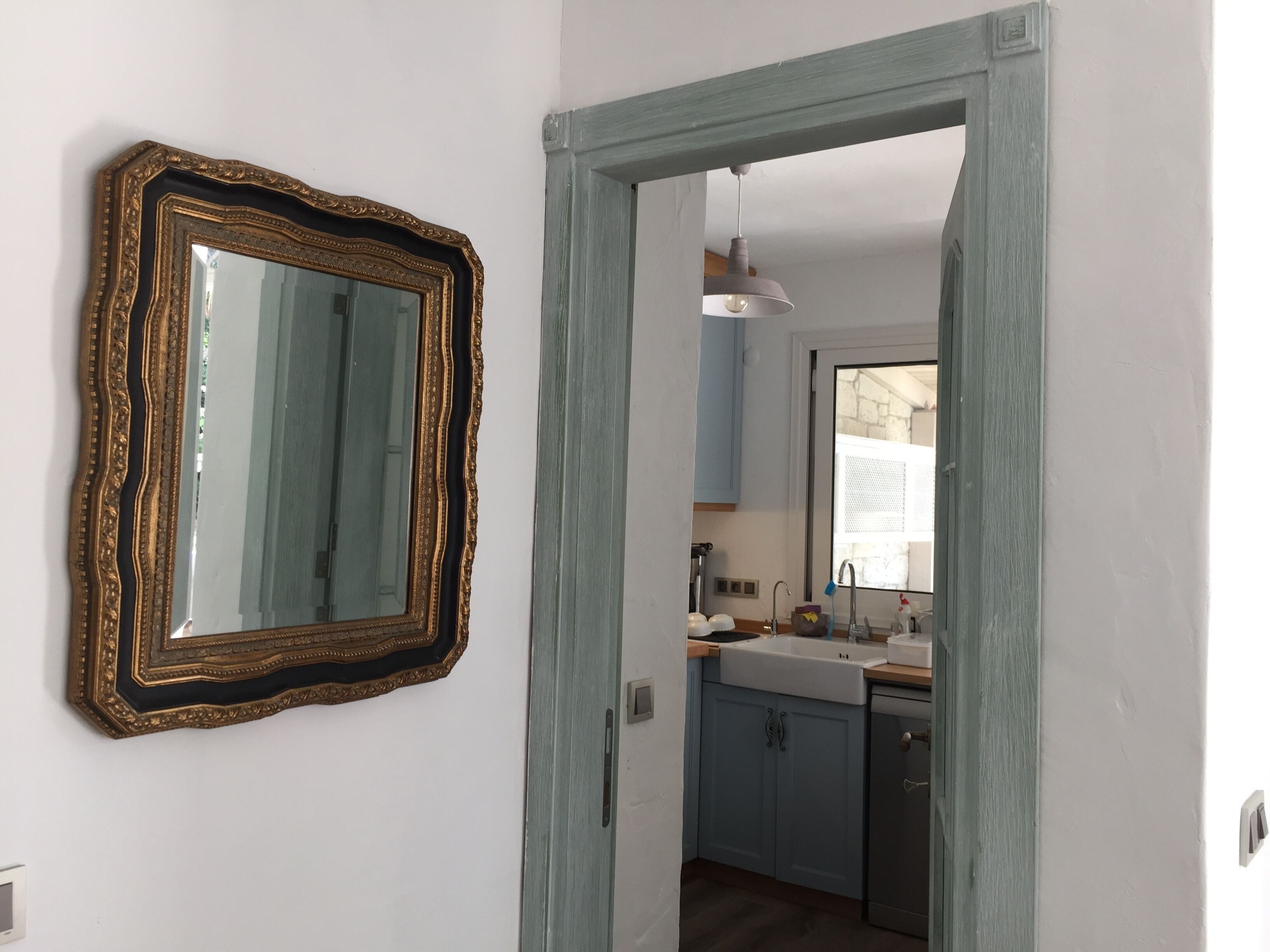 A kitchen with a sink, cabinets, and a mirror with an ornate frame.