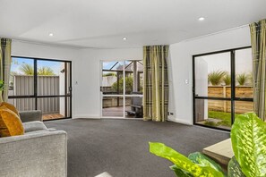 Een modern interieur met een grijze bank, een salontafel en een uitzicht door een glazen deur op een terras.