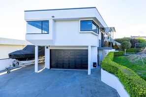 A modern two-story house with a garage, a covered carport, and a well-maintained garden. - Harvey Heights Retreat (Taupō)