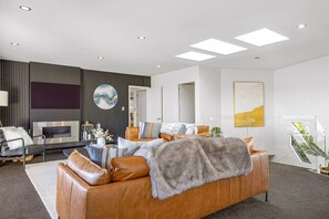 A modern living room with a leather sofa, a flat-screen TV, and a fireplace. - Harvey Heights Retreat (Taupō)