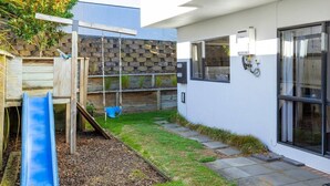 Un área de juegos al aire libre moderna con un tobogán, un columpio y una estructura para escalar.