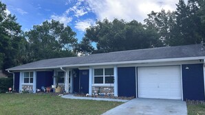 A single-story house with a garage, a front porch with a small garden, and a clear sky. - Homosassa Getaway 3/2 (Homosassa)