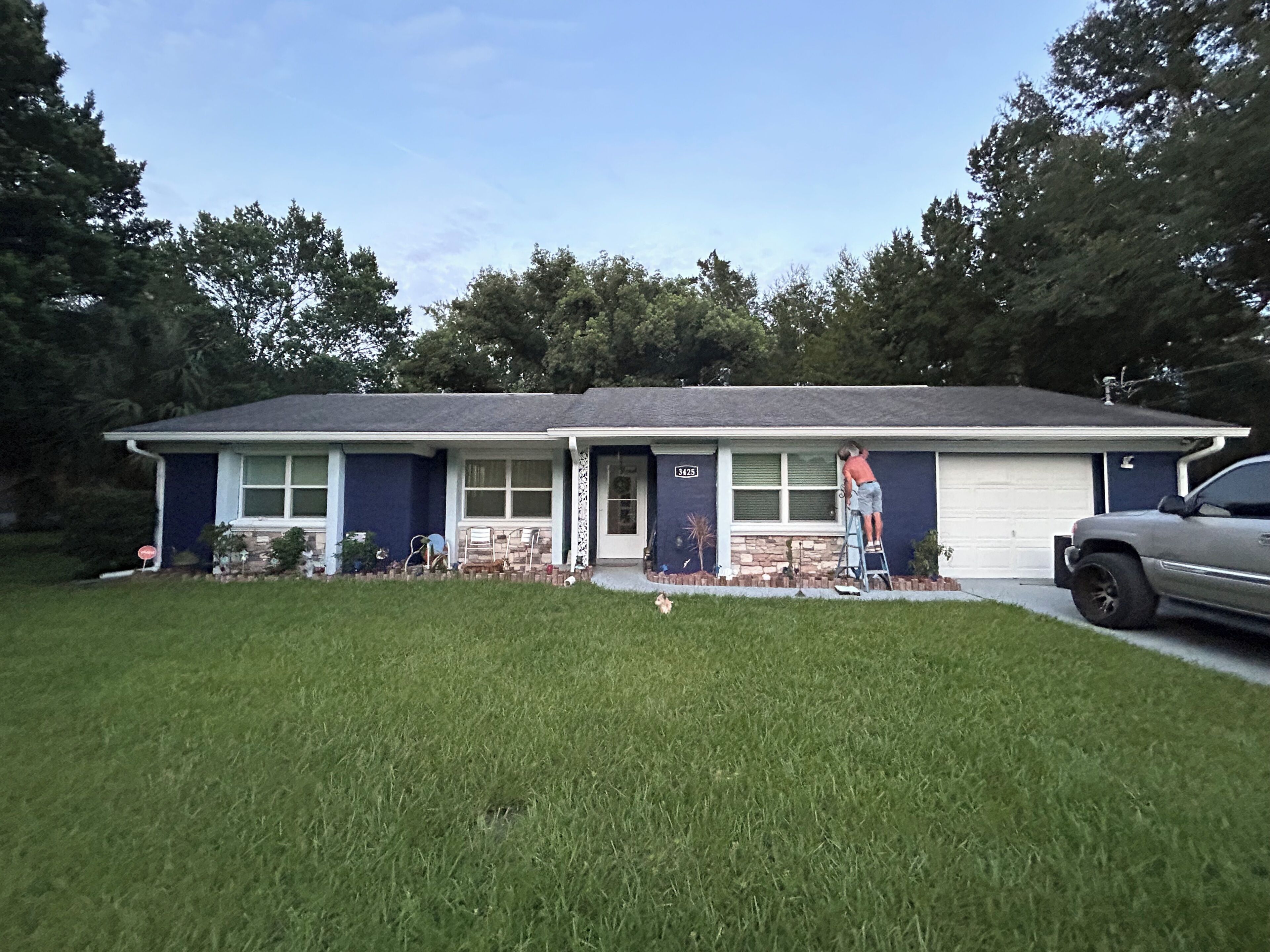 A single-story house with a garage, a front lawn, and a parked vehicle.