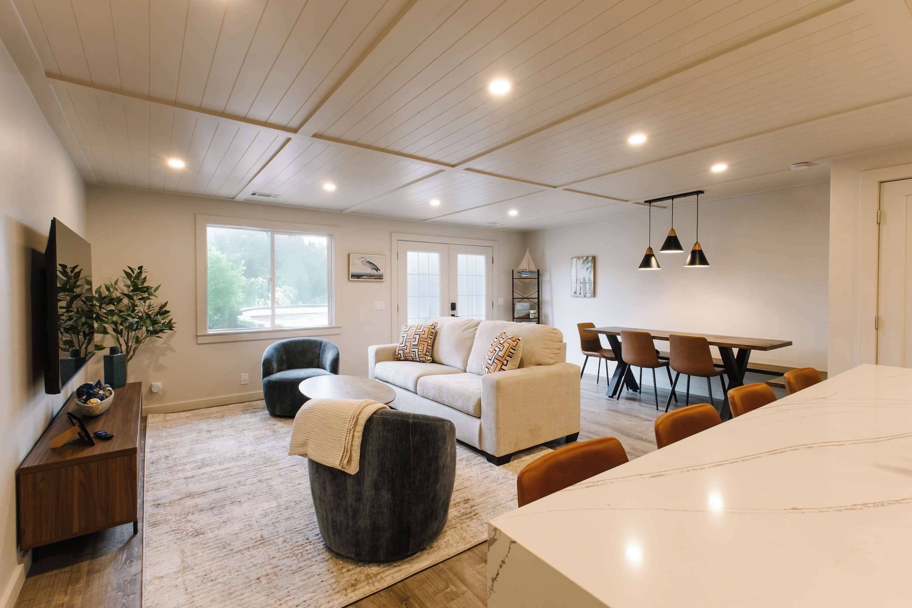 Un salon moderne avec un canapé, un pouf et une table à manger.