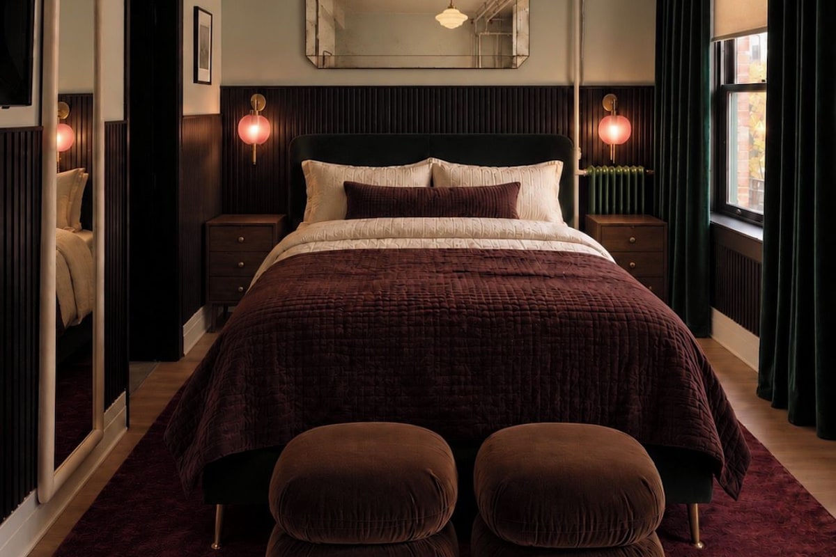 A modern bedroom with a large bed, two bedside tables, a mirror, and a window with curtains.